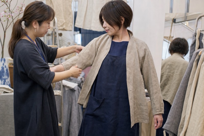 ハンドメイド服の試着を手伝う作家と来場者