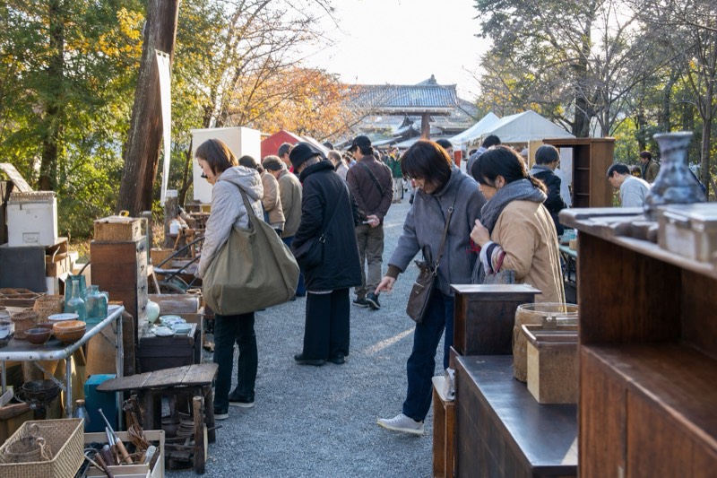 神社の参道に並ぶ蚤の市を見て歩く来場者