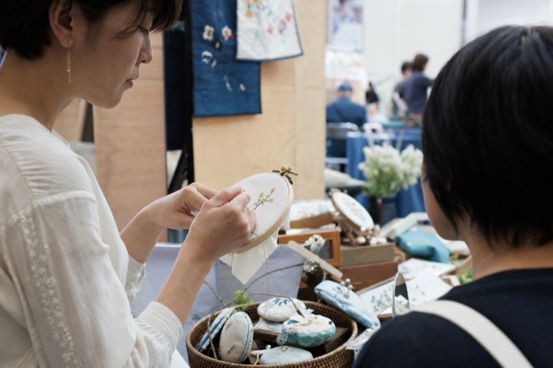 刺繍作品の制作を近くで見る来場者