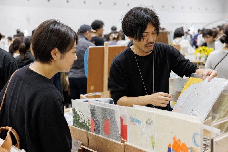 イラスト作品を作家と一緒に見る来場者