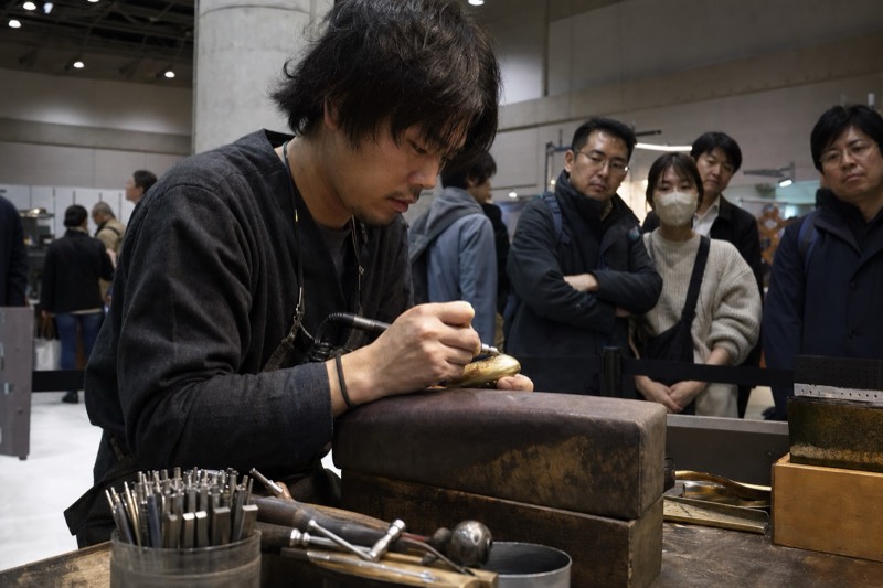 金工作家の制作実演を見学する来場者