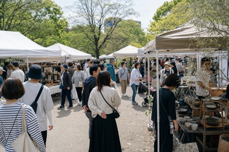 晴れた公園のハンドメイドイベントを歩く人々