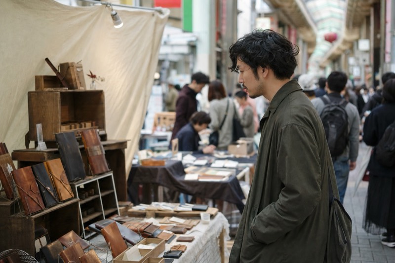 一人で紙ものや革小物を見る男性客